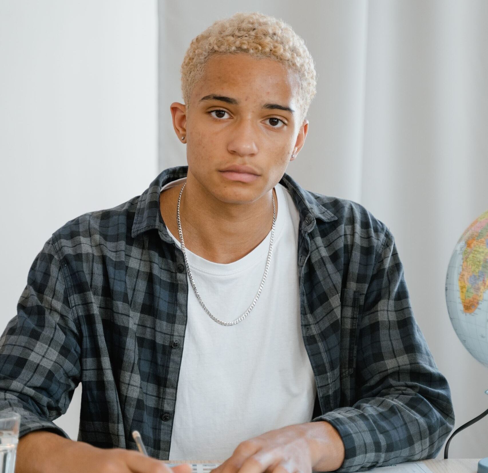 A focused teenager engaging in geographical studies with a map and globe indoors.