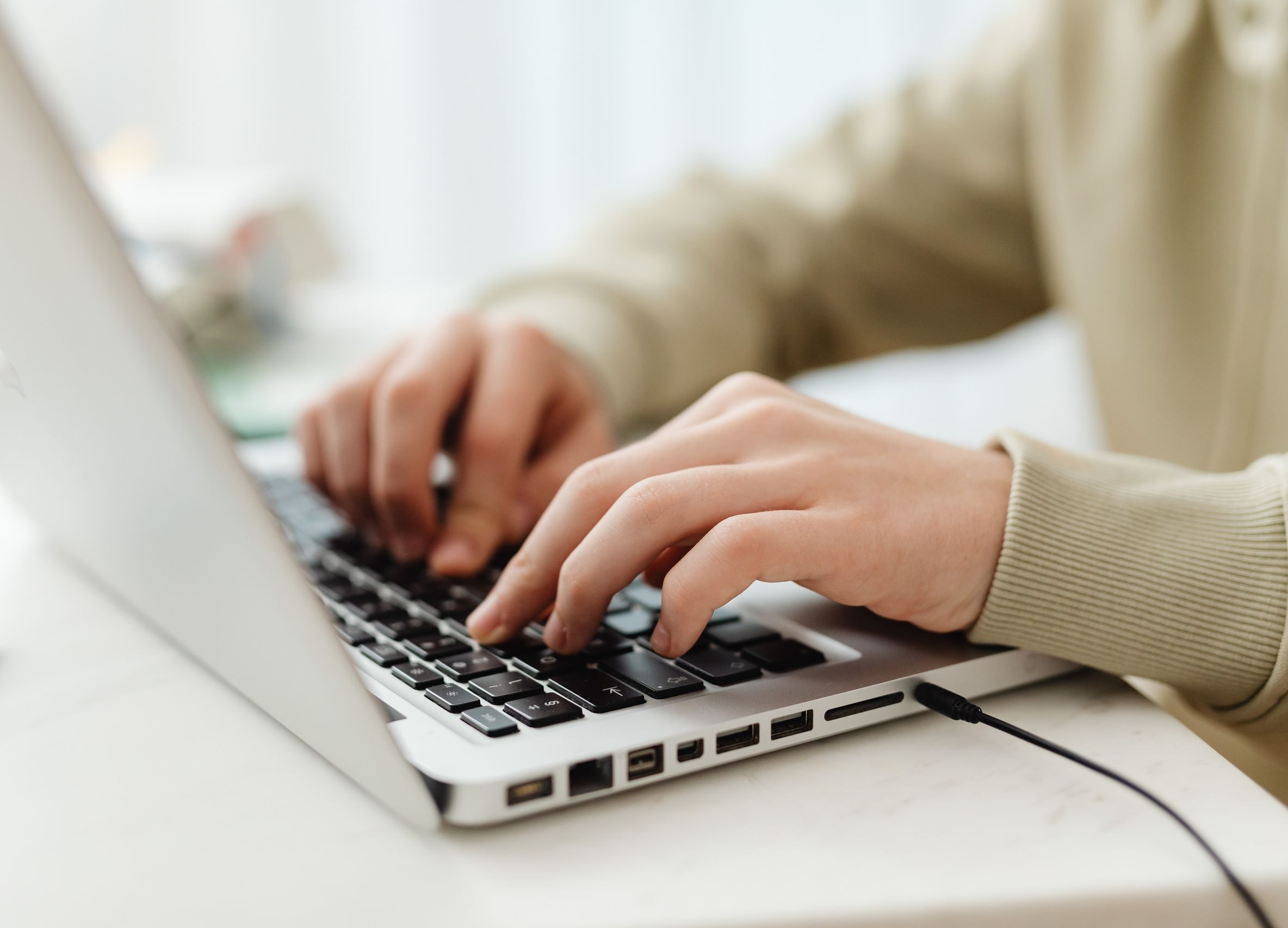 Close-up shot of hands typing on a laptop keyboard indoors, perfect for technology, business, and lifestyle themes.